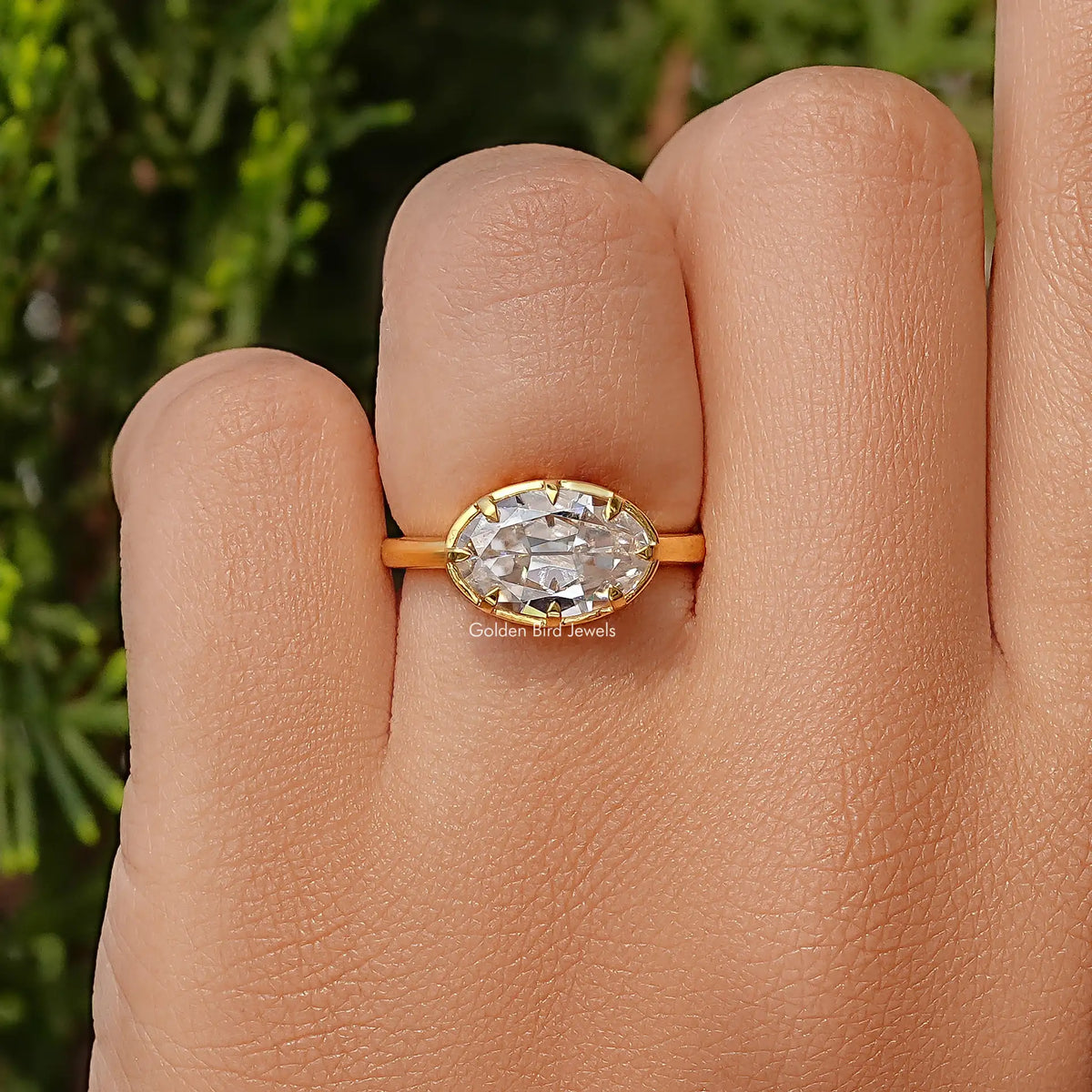 Oval moissanite solitaire ring close-up with gold-tone band and faceted center stone.