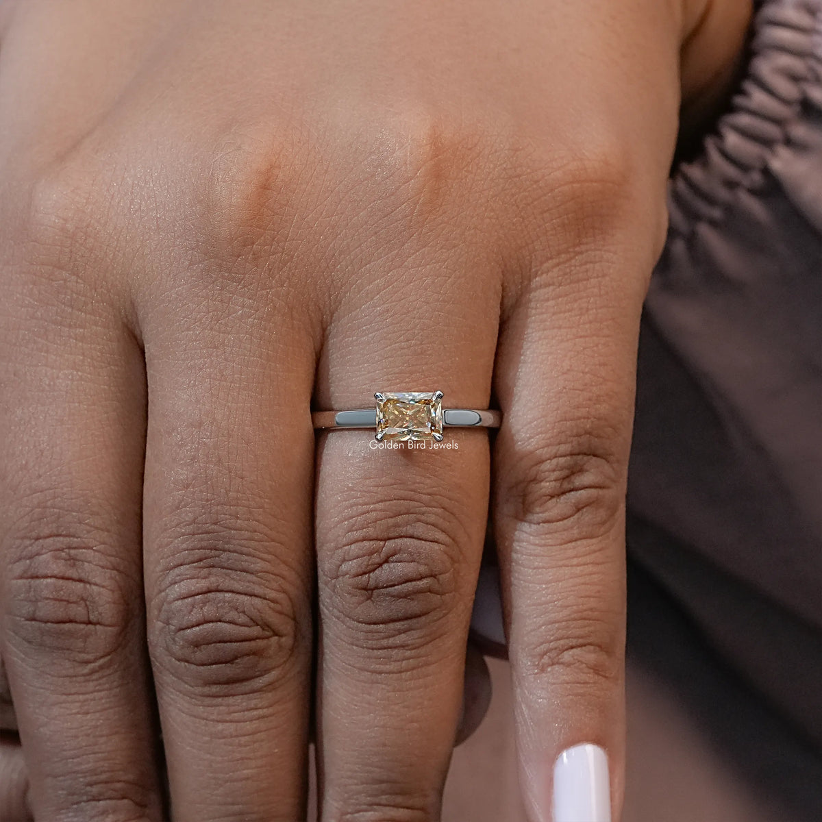 Yellow emerald-cut solitaire ring on silver-tone band, full hand portrait