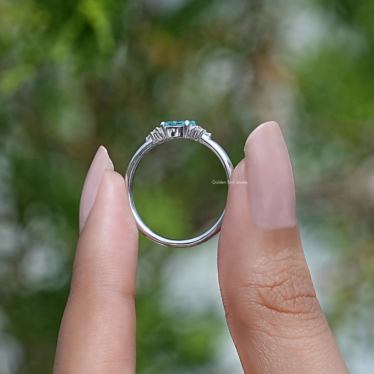 Back View of Emerald Cut Gemstone Engagement Ring In two fingers