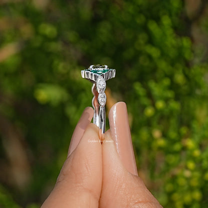 Silver-tone engagement ring with oval green stone, diamond halo, and side prongs