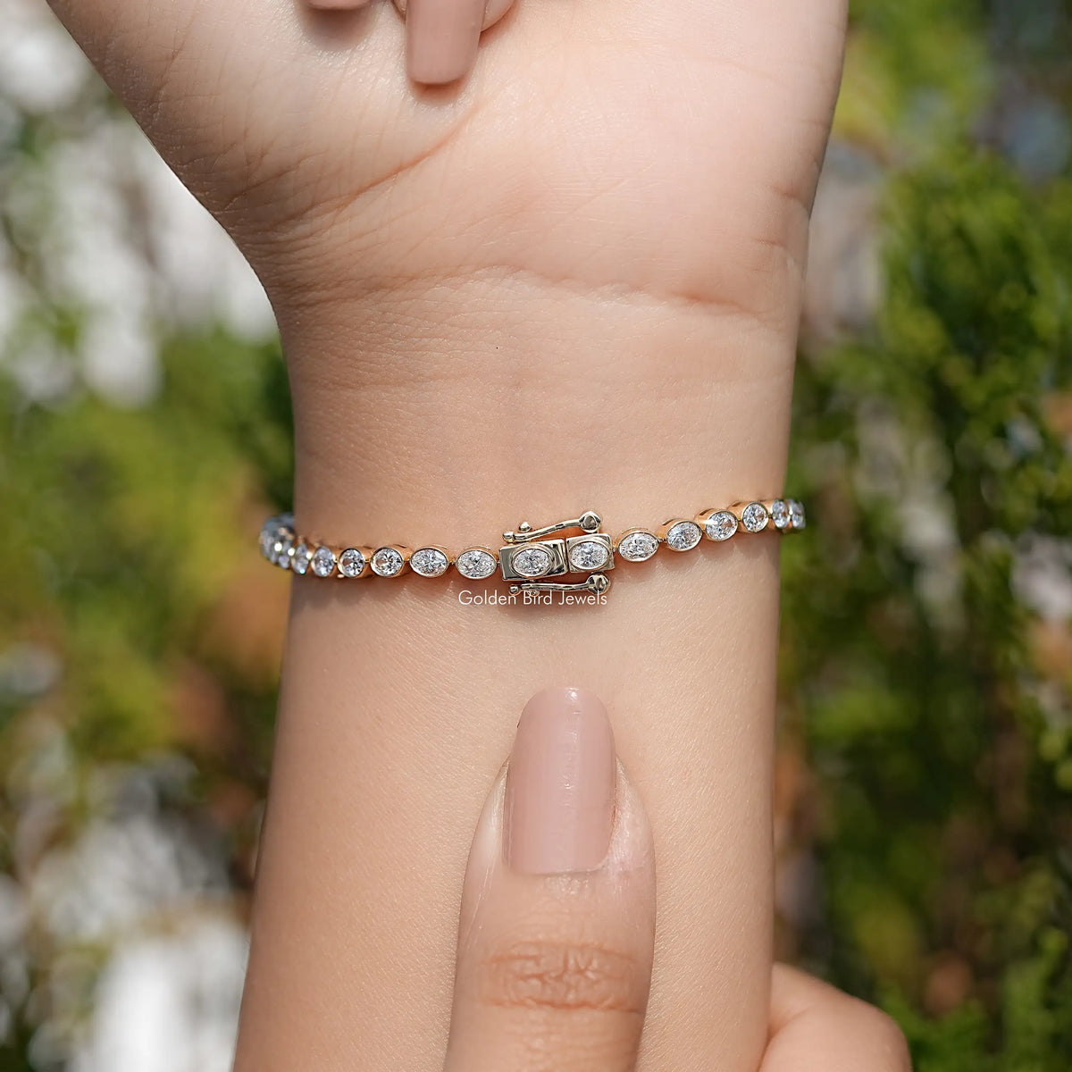 Silver-tone oval-cut diamond tennis bracelet across wrist with oval stone links