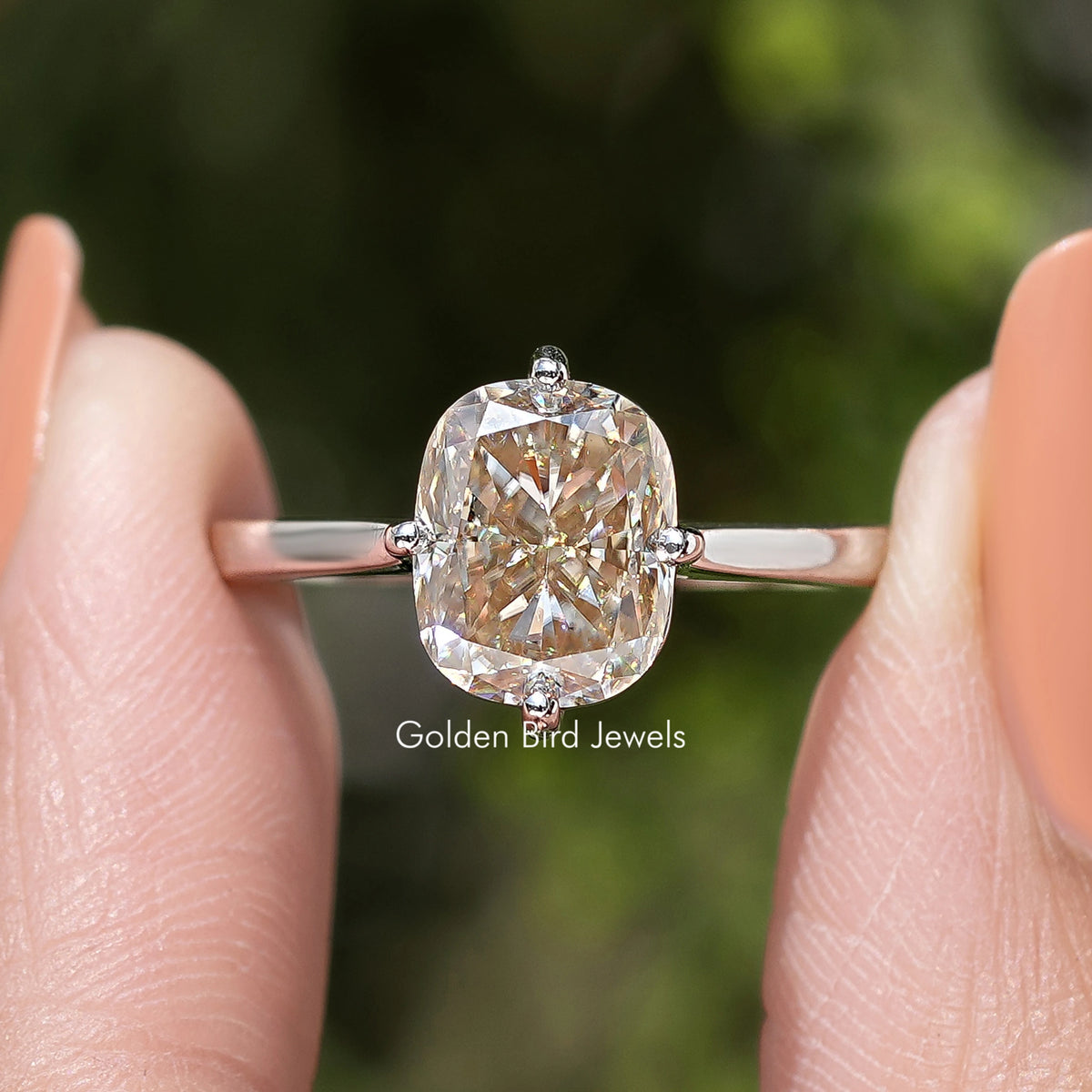 Front close-up of rose-gold tone elongated cushion-cut solitaire engagement ring on finger