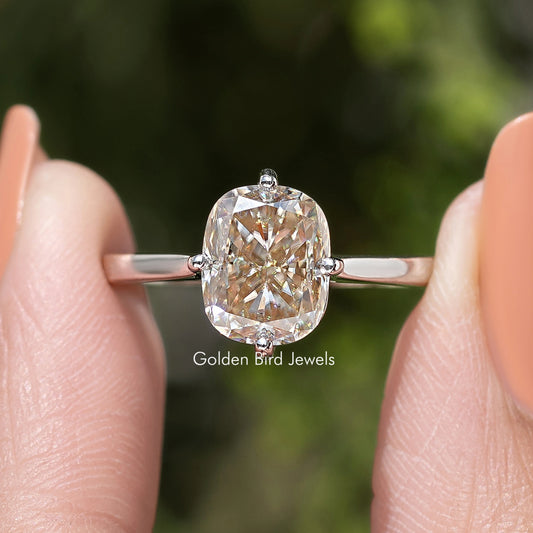 Front close-up of rose-gold tone elongated cushion-cut solitaire engagement ring on finger
