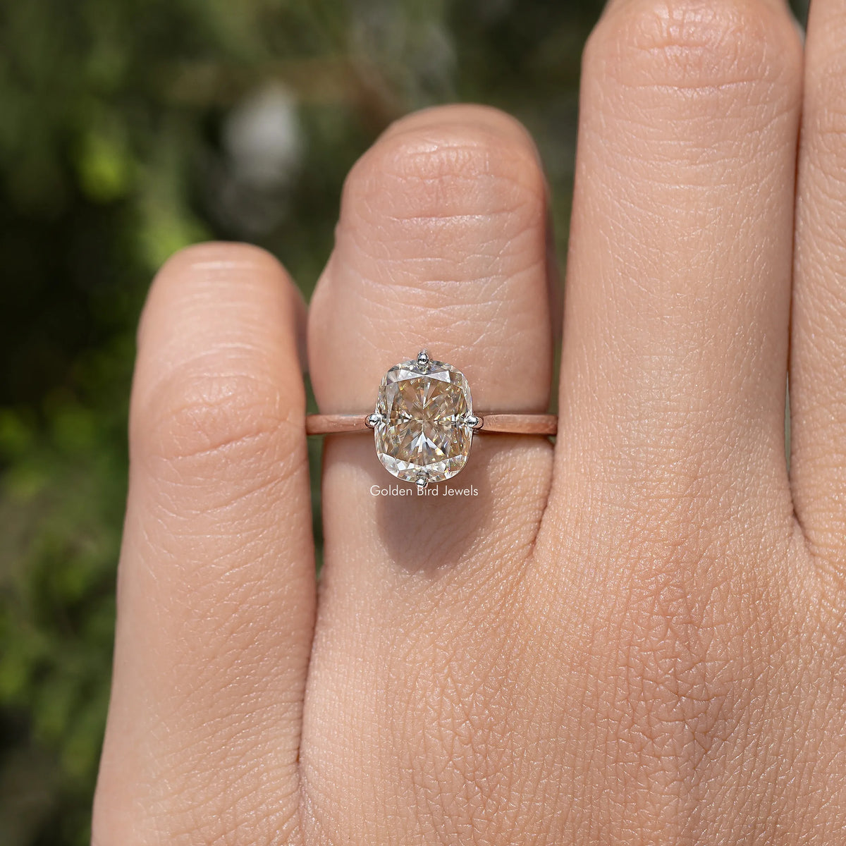 Elongated cushion-cut solitaire engagement ring on finger, rose-gold tone band
