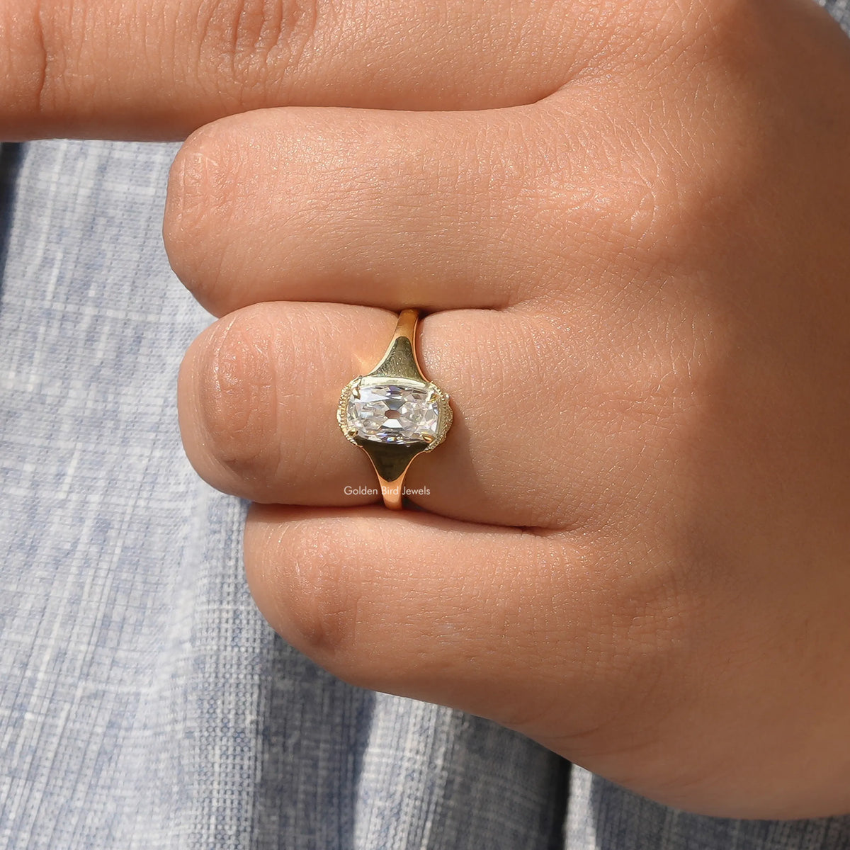 Elongated cushion-cut moissanite ring close-up with gold-toned halo setting