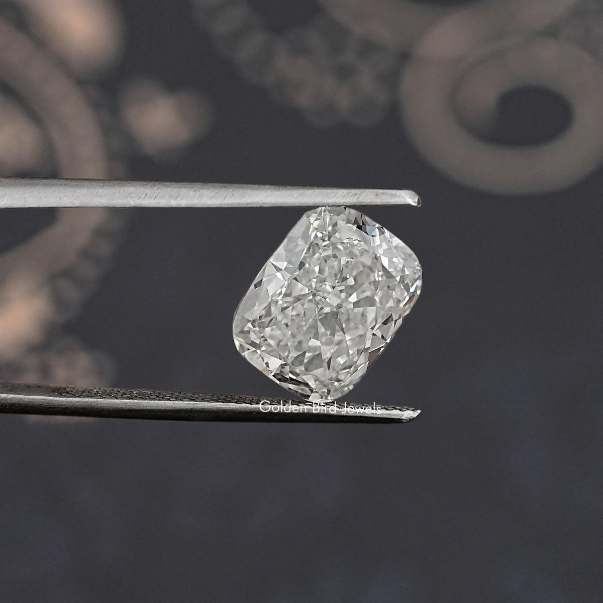 Loose lab-grown diamond, elongated cushion cut, icy white, held between metal tweezers.