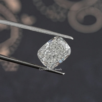 Loose elongated cushion-cut diamond held in metal tweezers, bright white sparkle