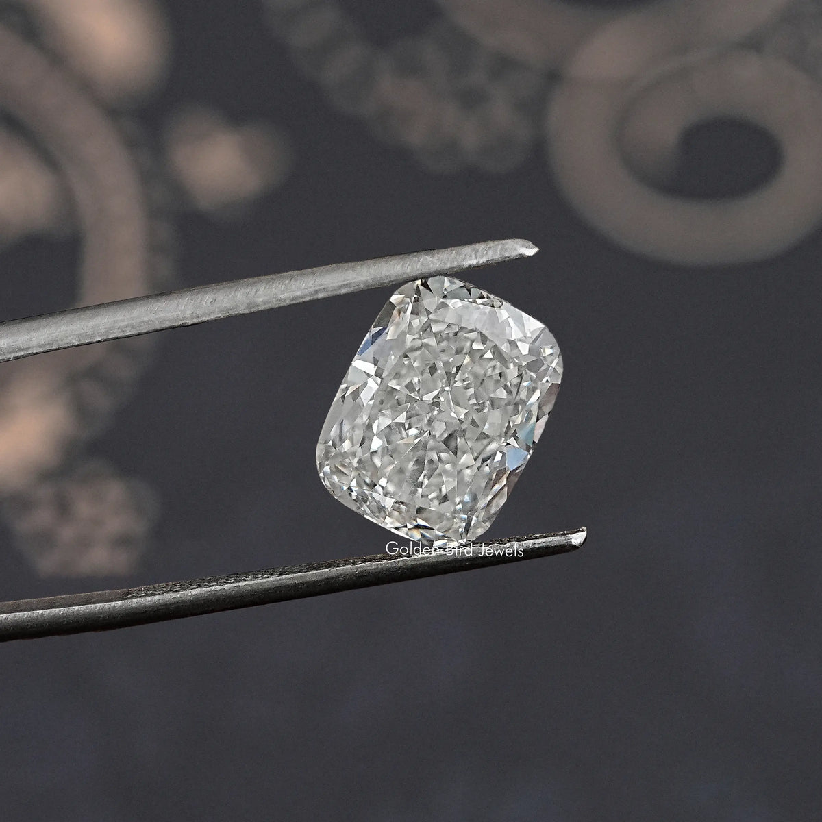 Loose lab-grown diamond, elongated cushion cut, bright white facets, held in tweezers.