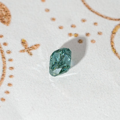 Elongated teal-green moissanite stone with prismatic faceting.