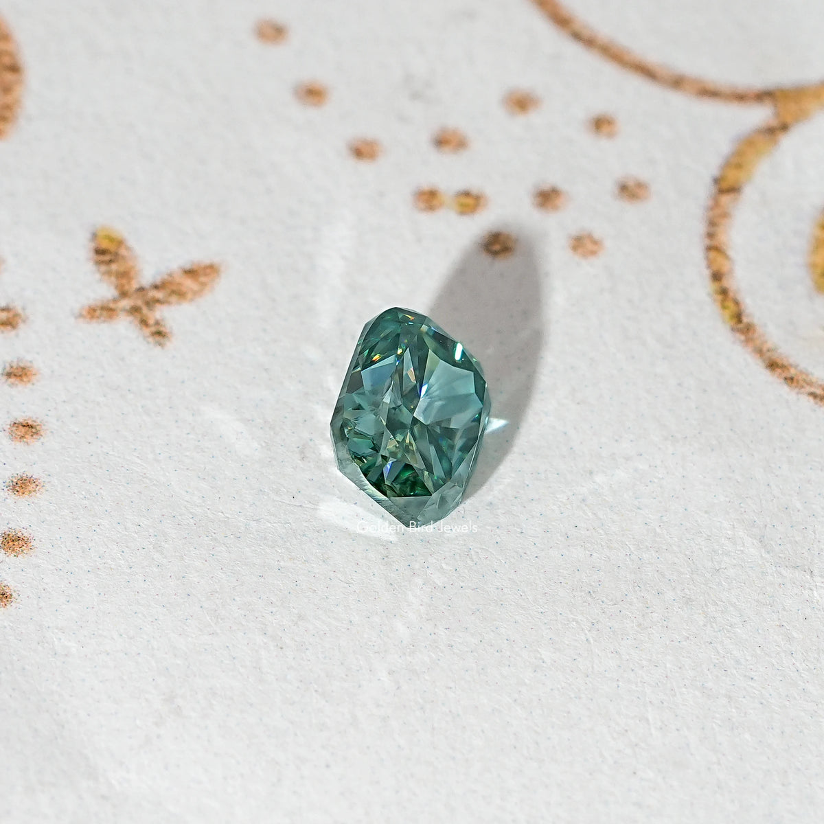 Elongated teal-green moissanite stone, angled view with sharp facets.