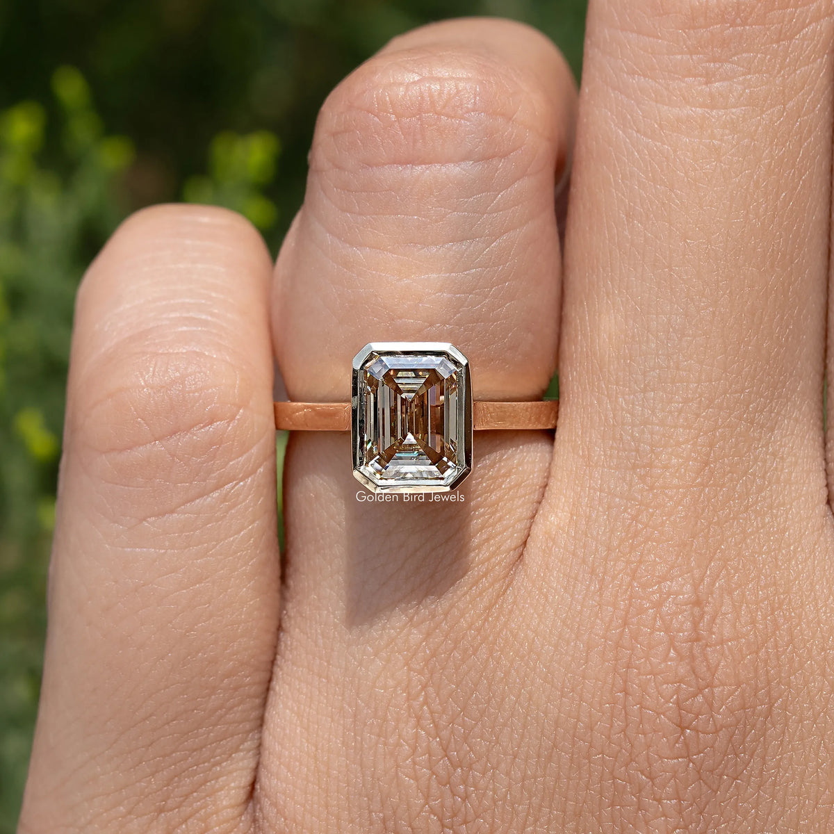 Rose-gold solitaire engagement ring featuring an emerald-cut center stone