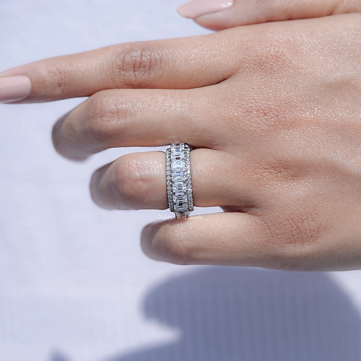 In finger front view of Emerald and Round Cut moissanite three row band  in unique shape