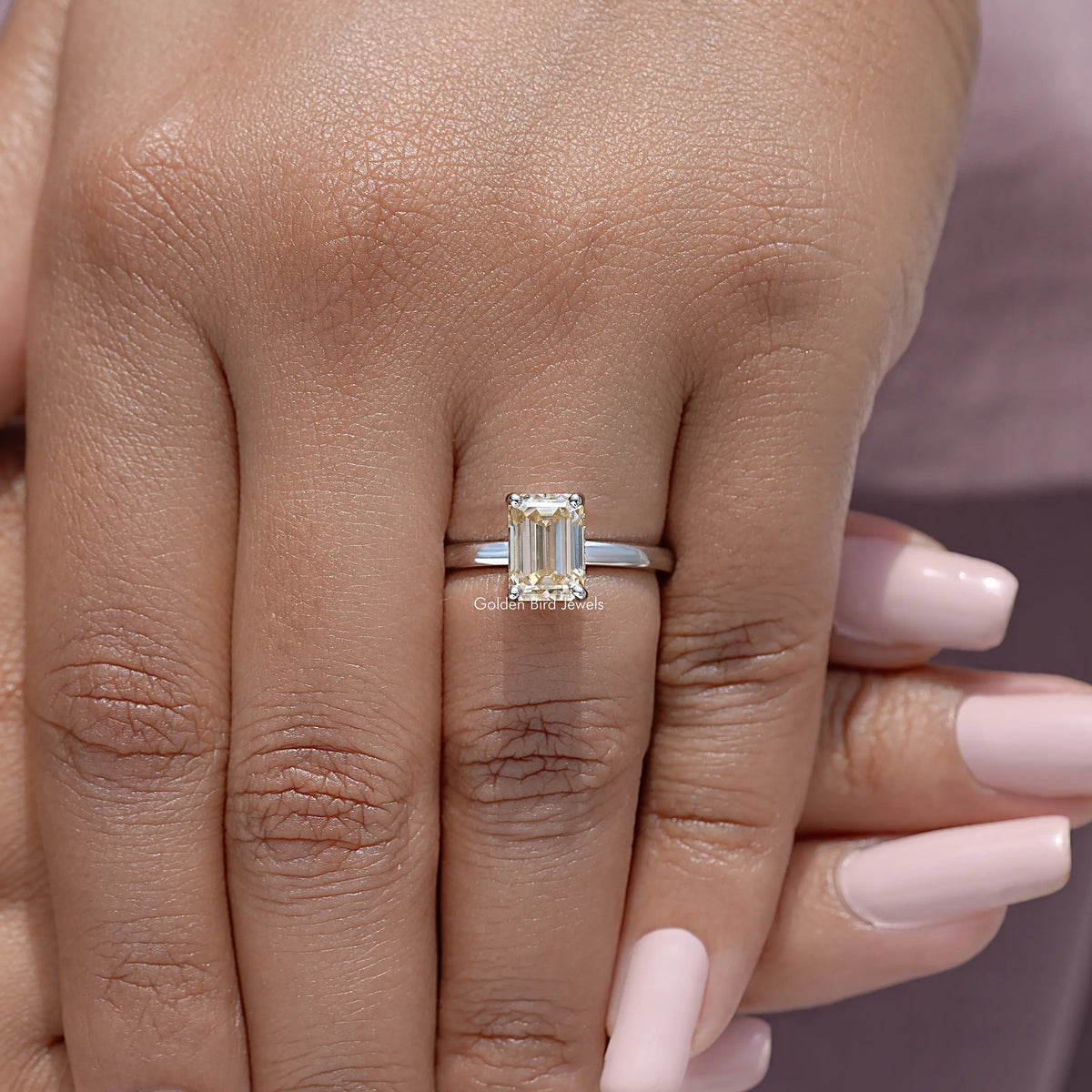 Yellow emerald-cut moissanite solitaire ring on finger, sterling silver band