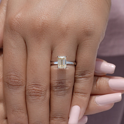 Yellow emerald-cut moissanite solitaire ring on finger, sterling silver band