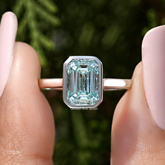 Front view of silver ring with emerald-cut blue moissanite in bezel setting