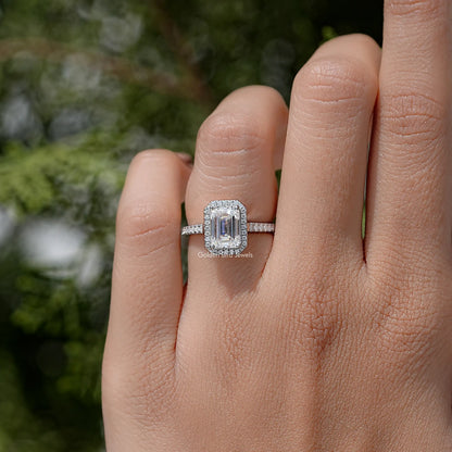 Sterling silver moissanite solitaire ring with emerald-cut center stone in halo-style frame.