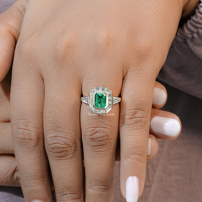 Halo engagement ring with emerald-green square gemstone on silver band, on hand close-up
