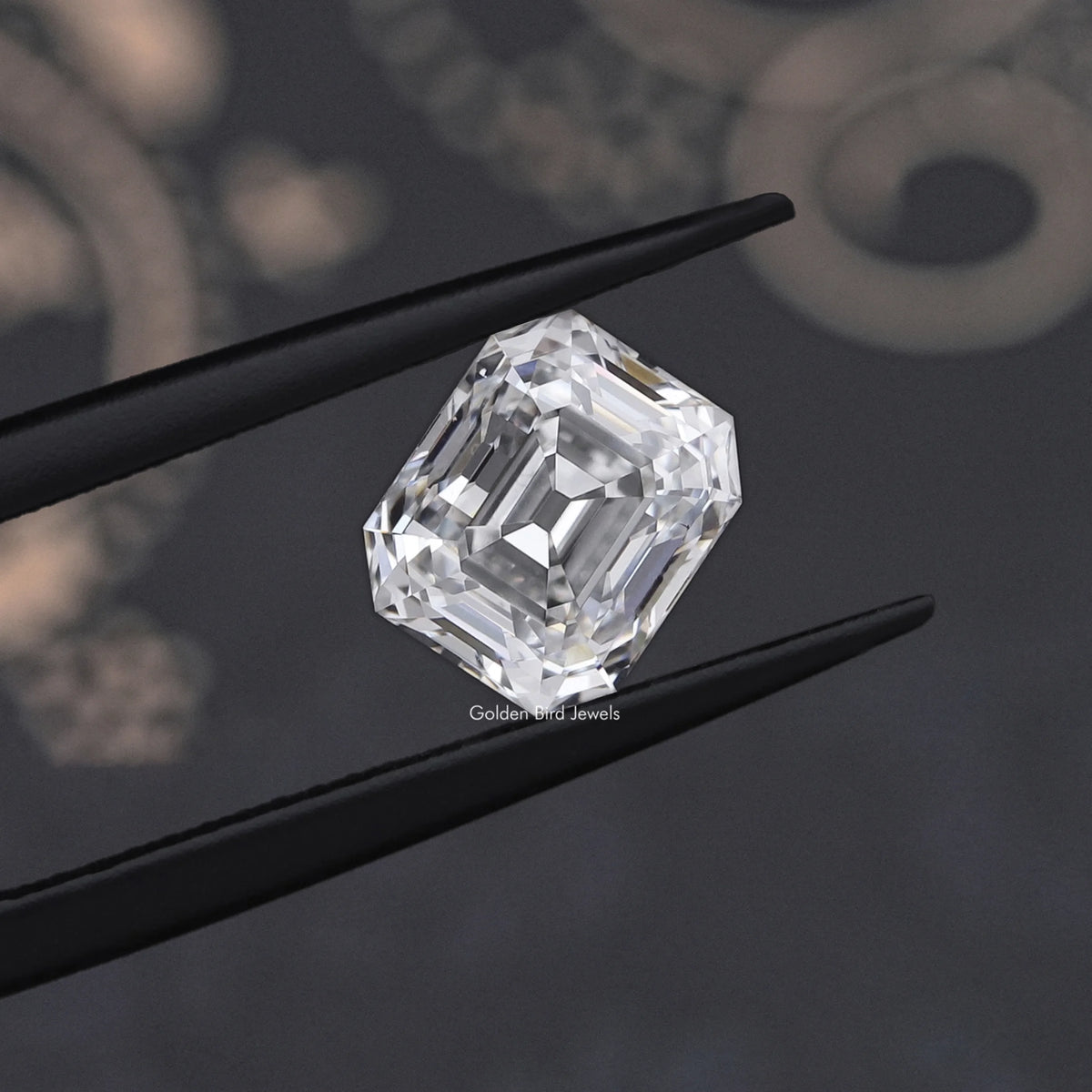 Emerald-cut lab-grown diamond held by black tweezers, angled view