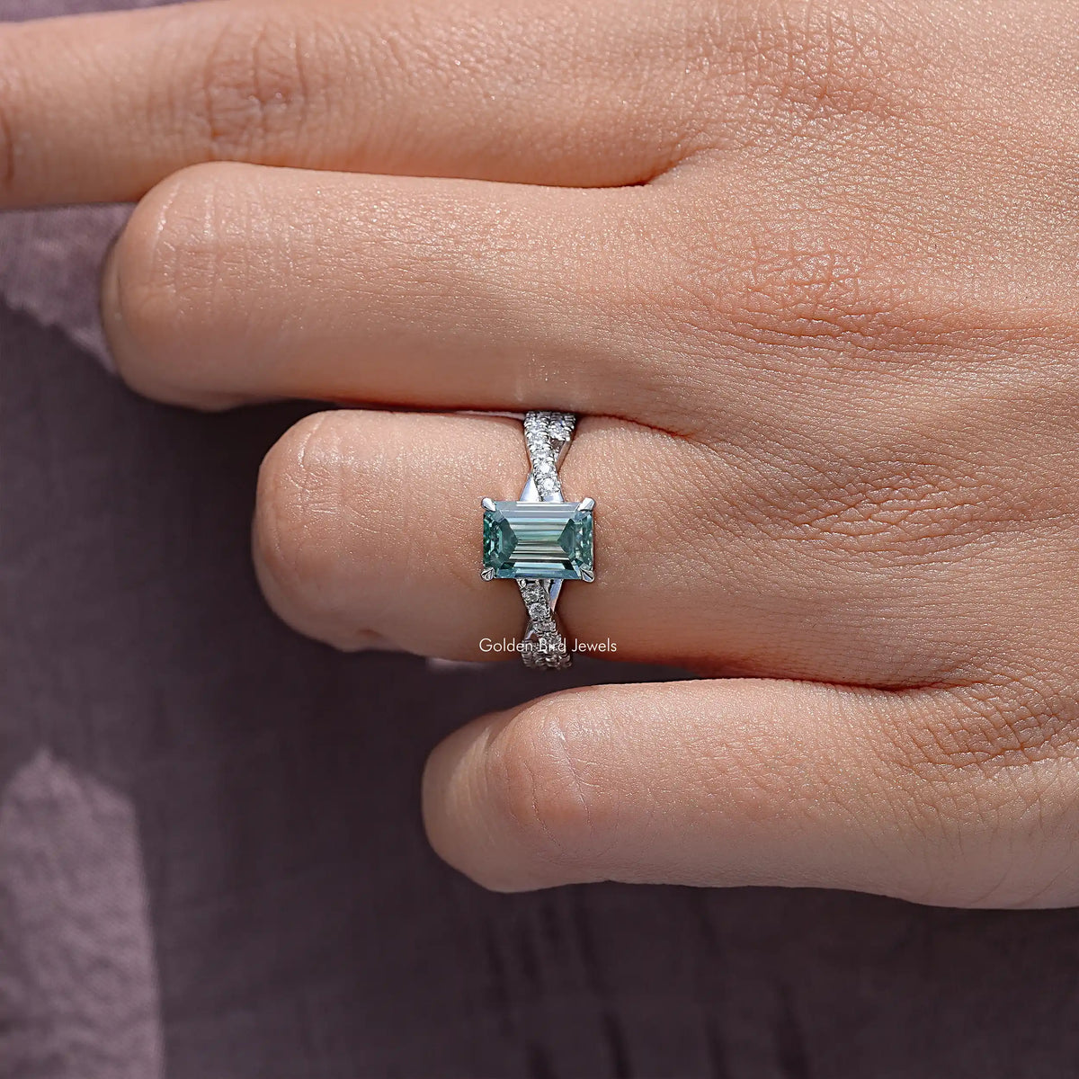 Teal emerald-cut moissanite wedding ring with twisted silver band, side view