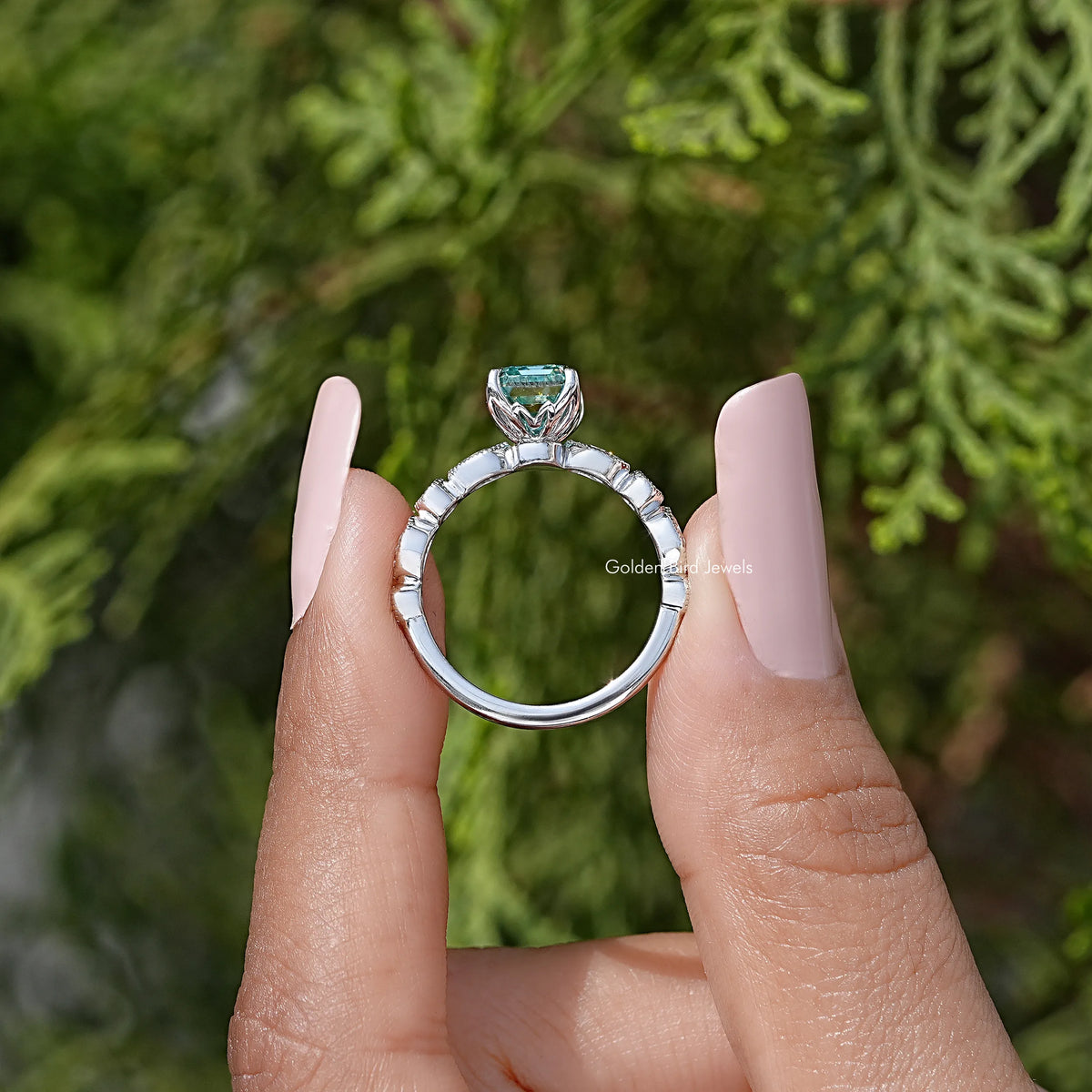 Emerald-cut moissanite ring open-back view, silver band with teal center setting.