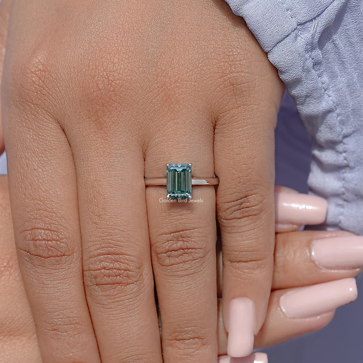 Emerald-cut moissanite solitaire ring with teal gemstone and slim silver band
