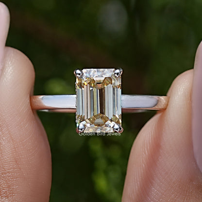 Macro view of yellow emerald-cut moissanite solitaire ring, sterling silver prongs