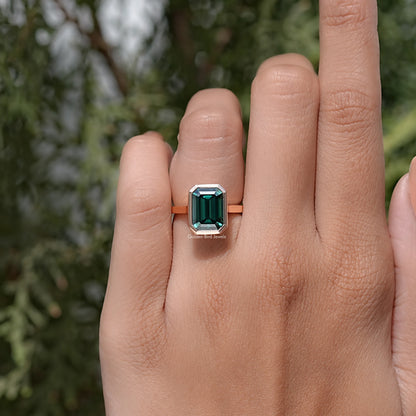 Emerald green moissanite solitaire ring on hand, rose gold-tone bezel setting