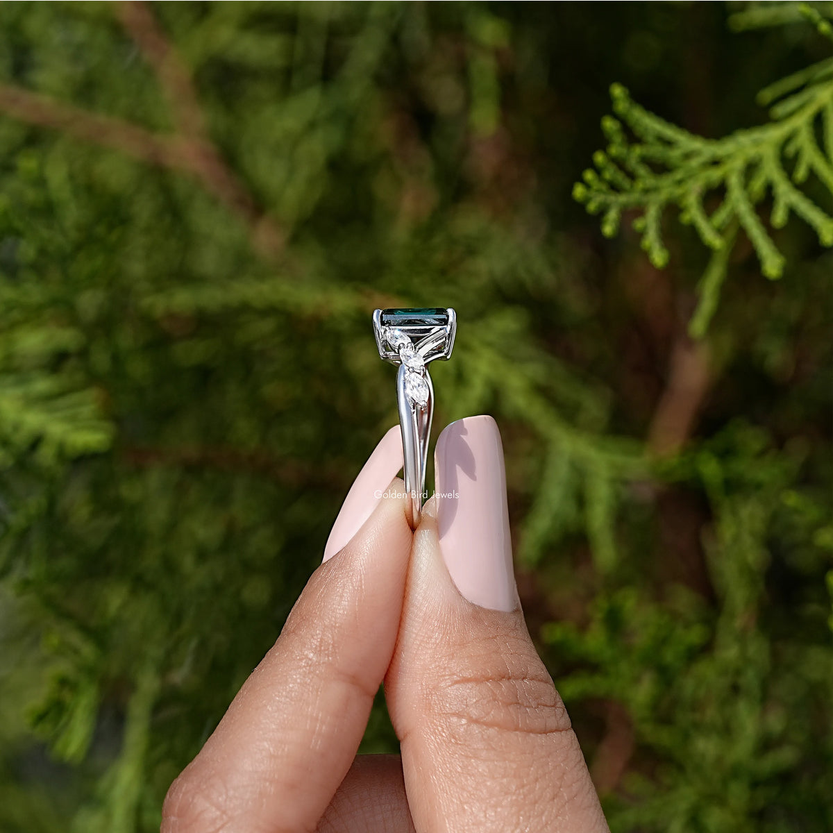 Sterling silver ring with green emerald-cut center stone in raised prongs.