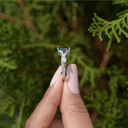 Sterling silver ring with green emerald-cut center stone in raised prongs.