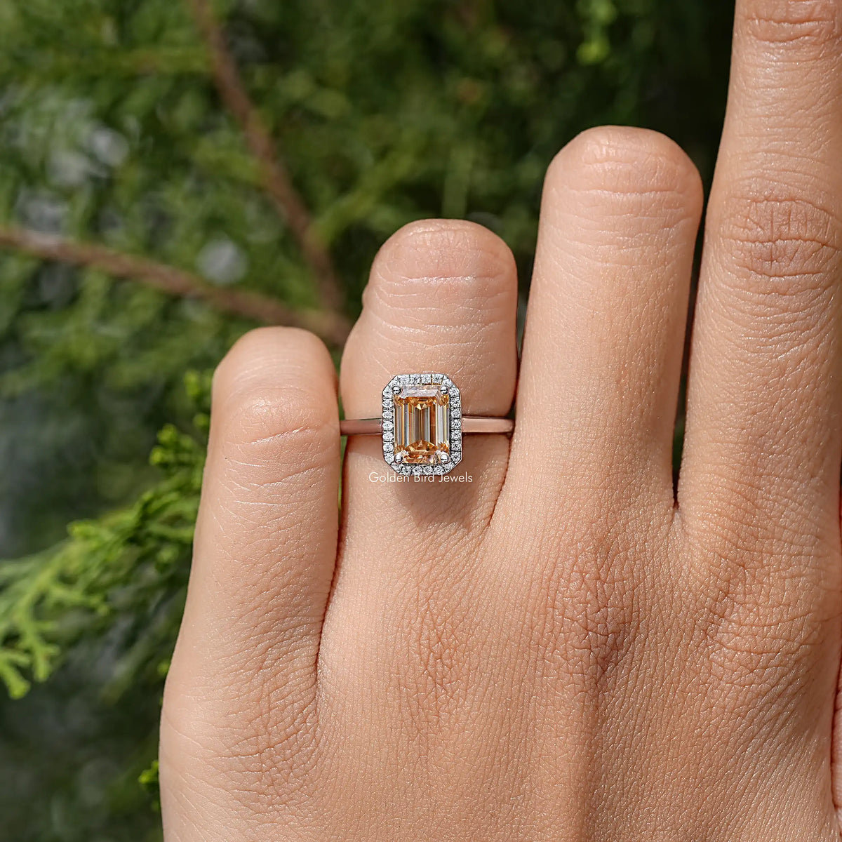 Sterling silver emerald-cut halo ring on finger, centered view