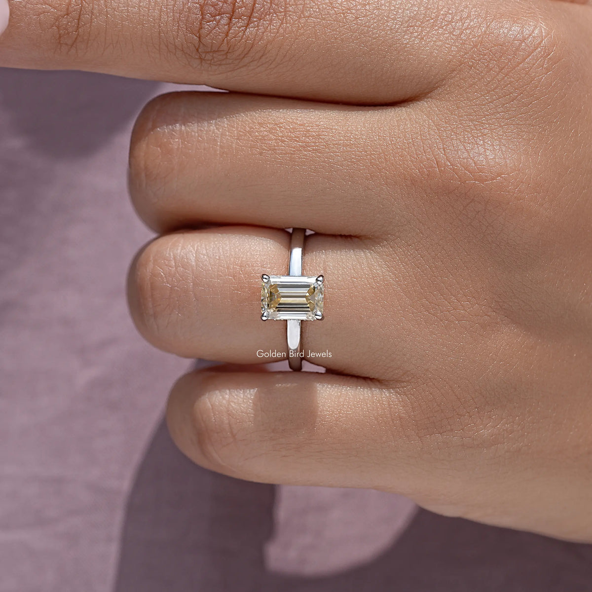 Close-up of sterling silver solitaire ring with yellow emerald-cut moissanite