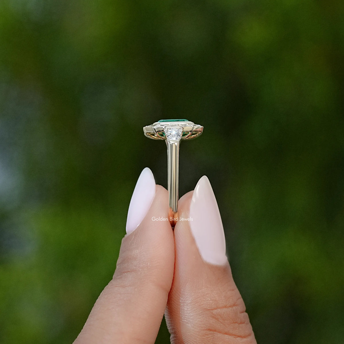 Silver ring with emerald-green gemstone bezel and prong setting, side profile
