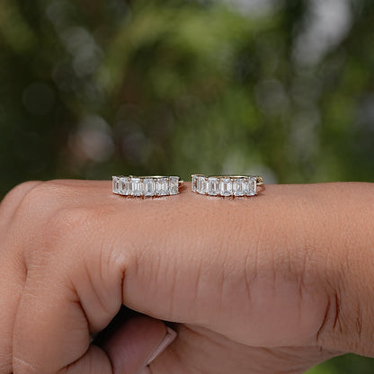 Gold-tone emerald-cut lab diamond hoop and huggie earrings on hand for side view