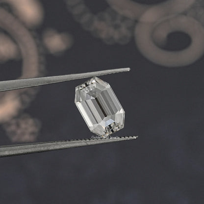 Emerald-cut lab-grown diamond tilted between metal tweezers, close-up