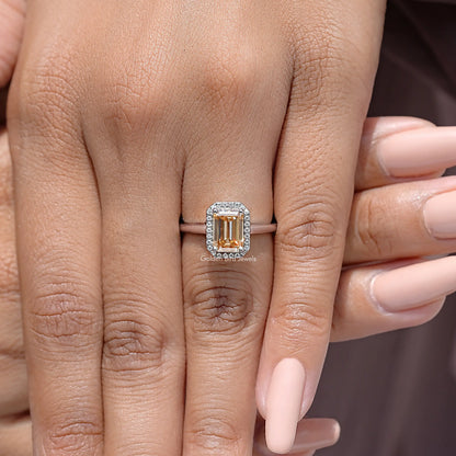 Sterling silver emerald-cut moissanite ring with round-stone halo, shown on finger