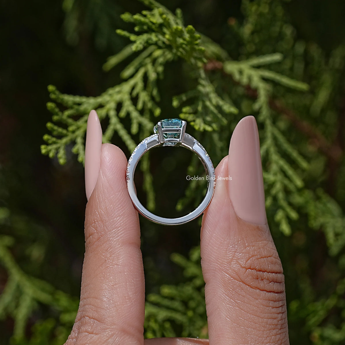 Silver twisted wedding ring with emerald-cut teal moissanite center viewed from front