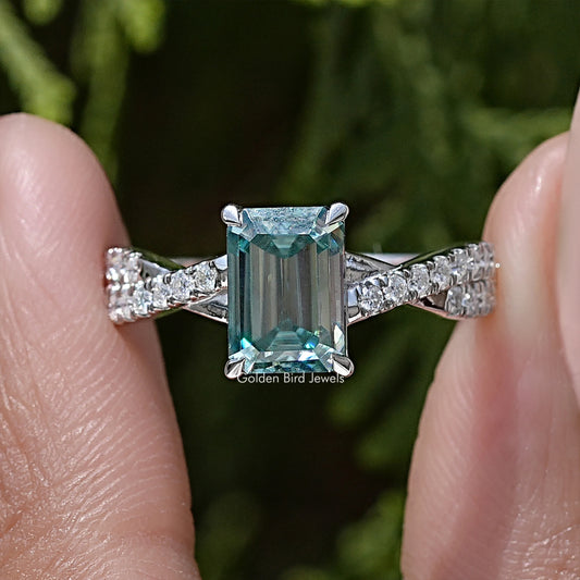 Emerald-cut moissanite twisted wedding ring with silver band and teal center stone