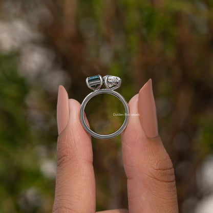 Two-stone ring with square emerald-cut green center and pear-cut clear side stones