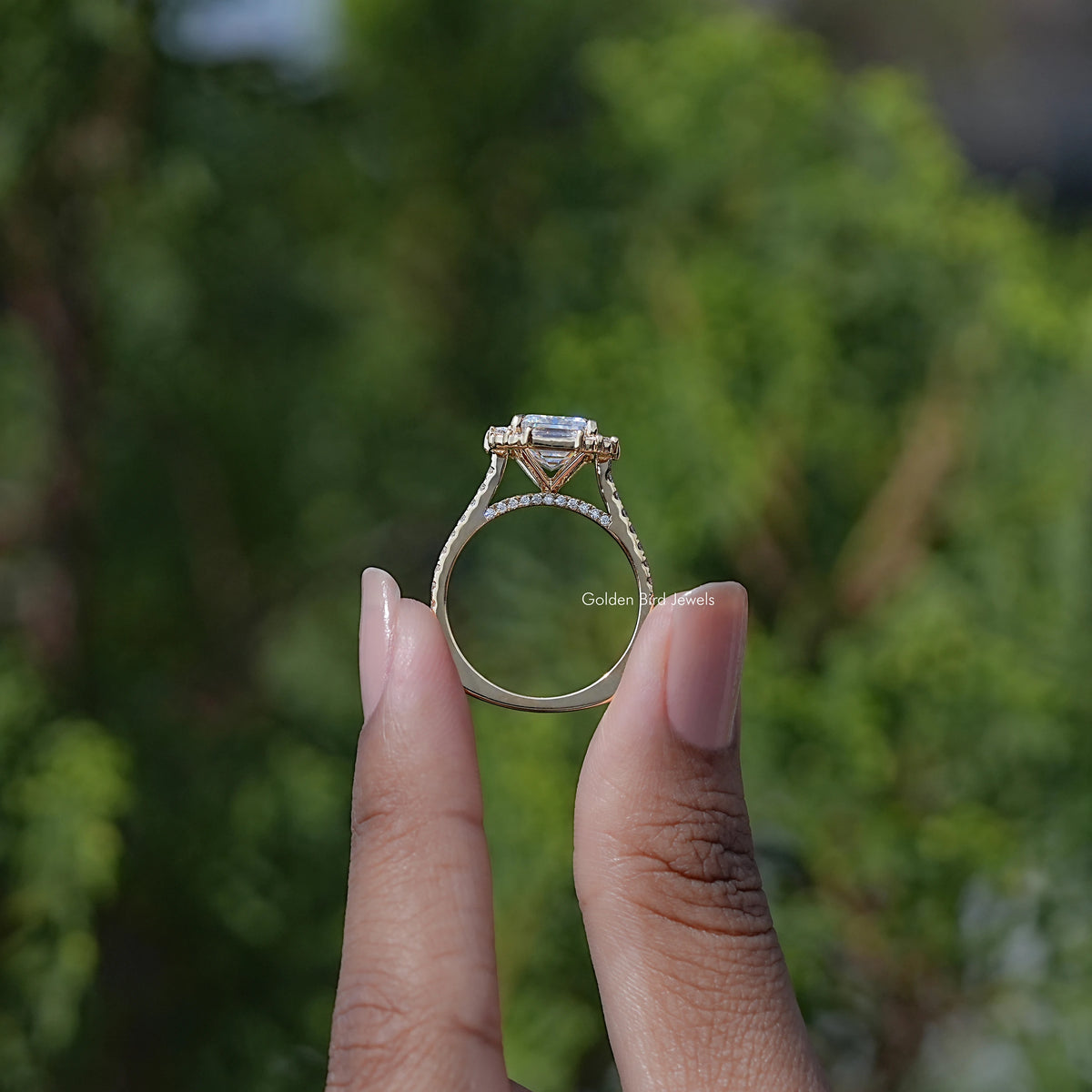 Emerald-cut halo moissanite engagement ring with baguette detail, side profile