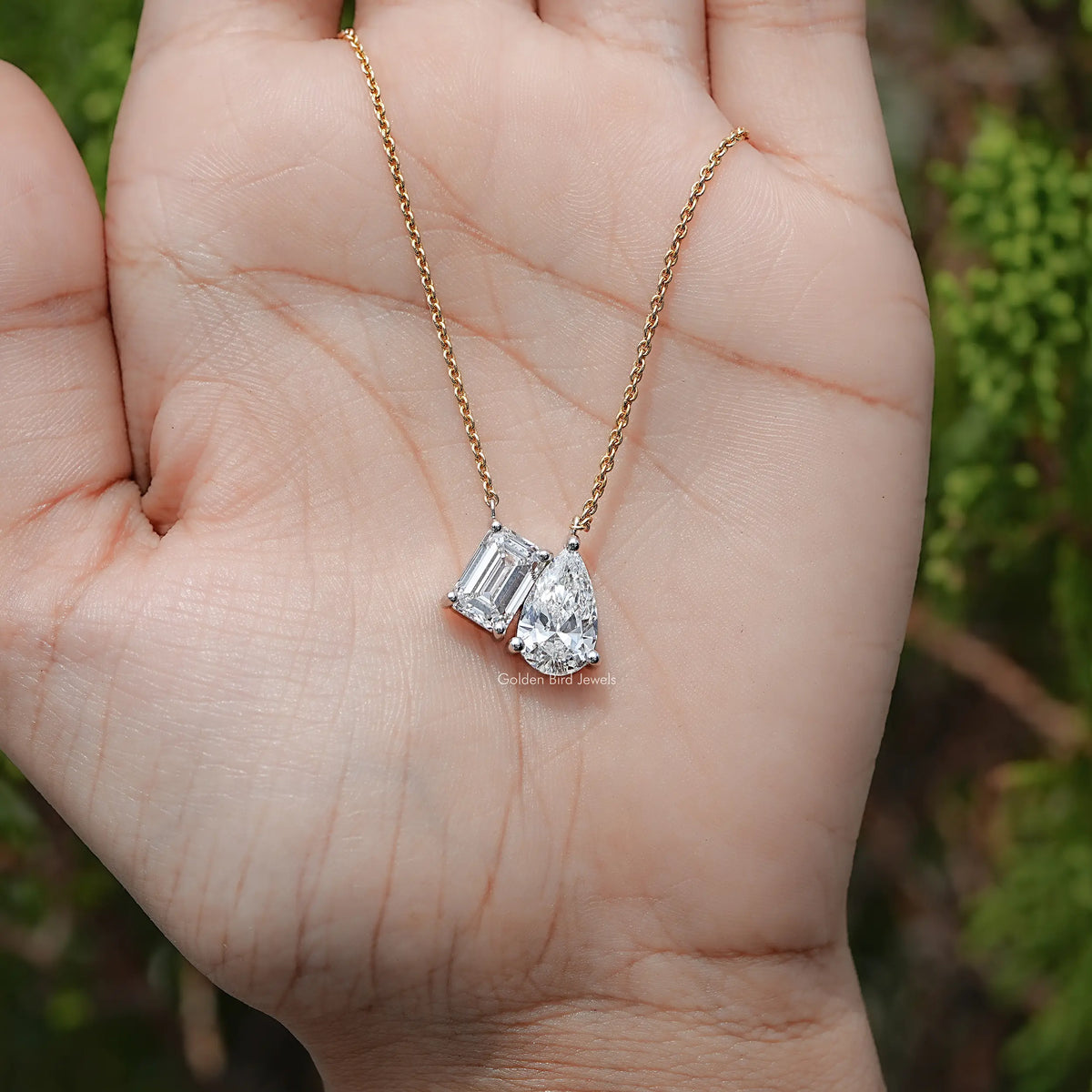 Gold two-stone lab diamond pendant necklace close-up; baguette and pear-cut stones