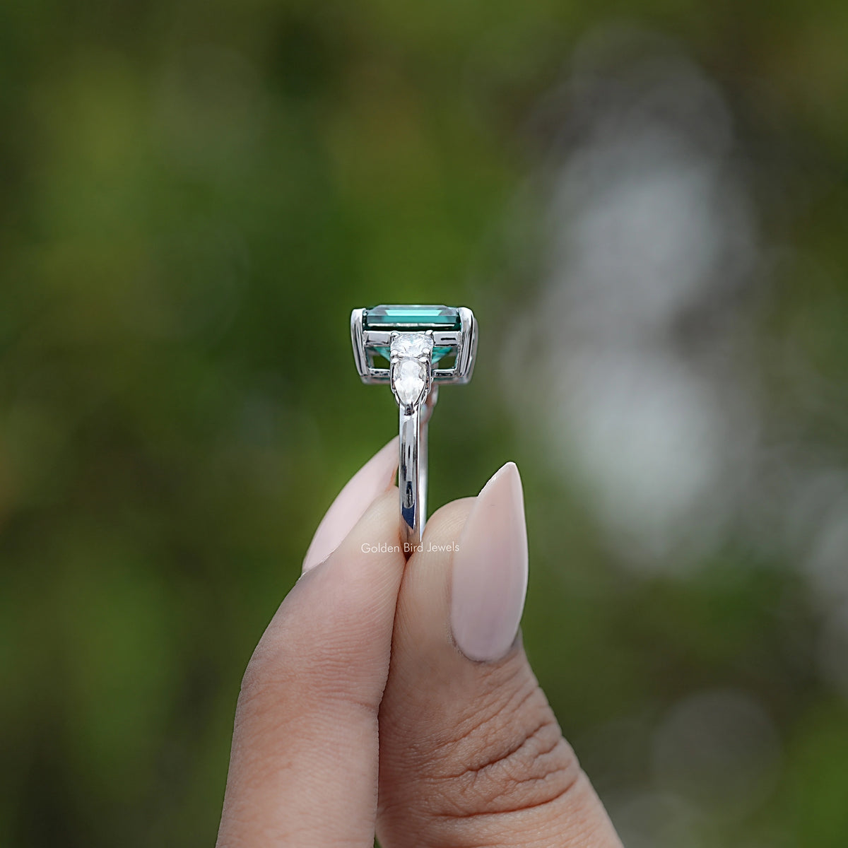 925 sterling silver ring with emerald-cut green center stone and side prongs visible