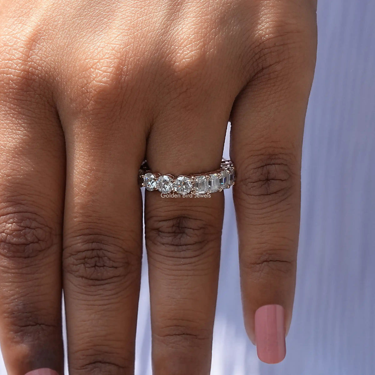 Round-cut moissanite band ring on hand, straight-on front view