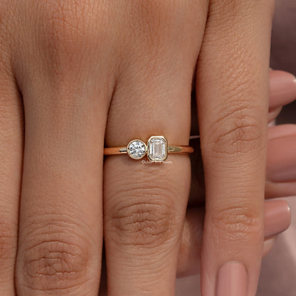 Gold-tone toi et moi ring on finger featuring round and emerald-cut lab diamonds