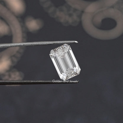 Loose emerald-cut lab-grown diamond held between tweezers, showing table and facets