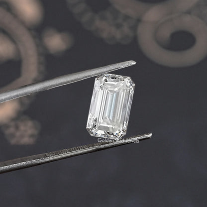 Loose emerald-cut lab-grown diamond held by tweezers, angled view of step cut
