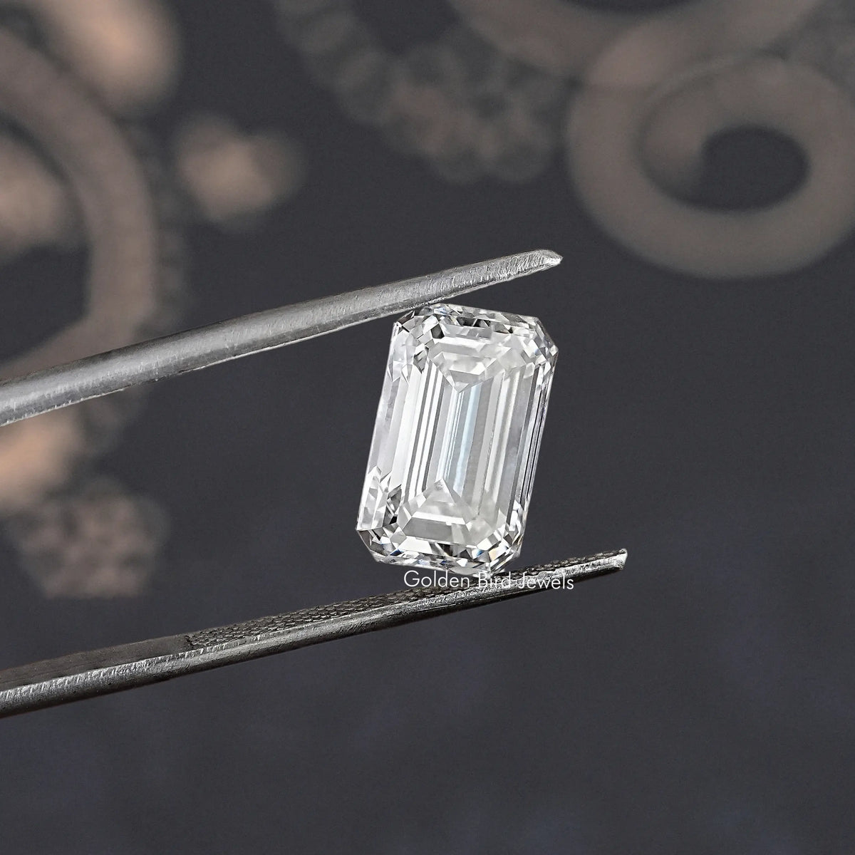 Loose emerald-cut lab diamond, clear rectangular stone held in tweezers, angled view