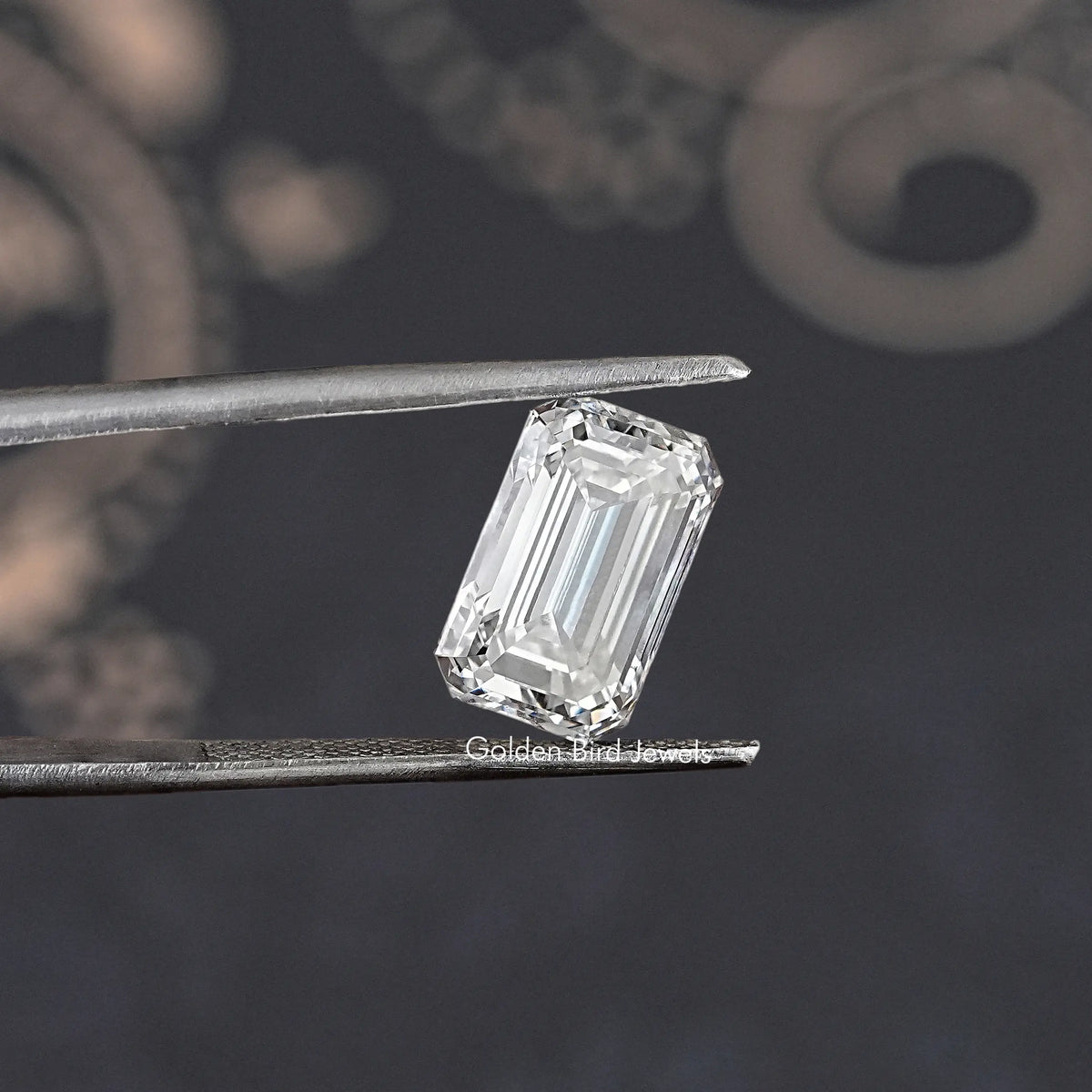 Loose emerald-cut lab-grown diamond held by tweezers, front view of step facets