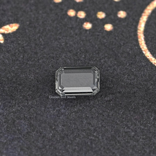 Emerald-cut loose diamond close-up, clear rectangular stone with stepped facets