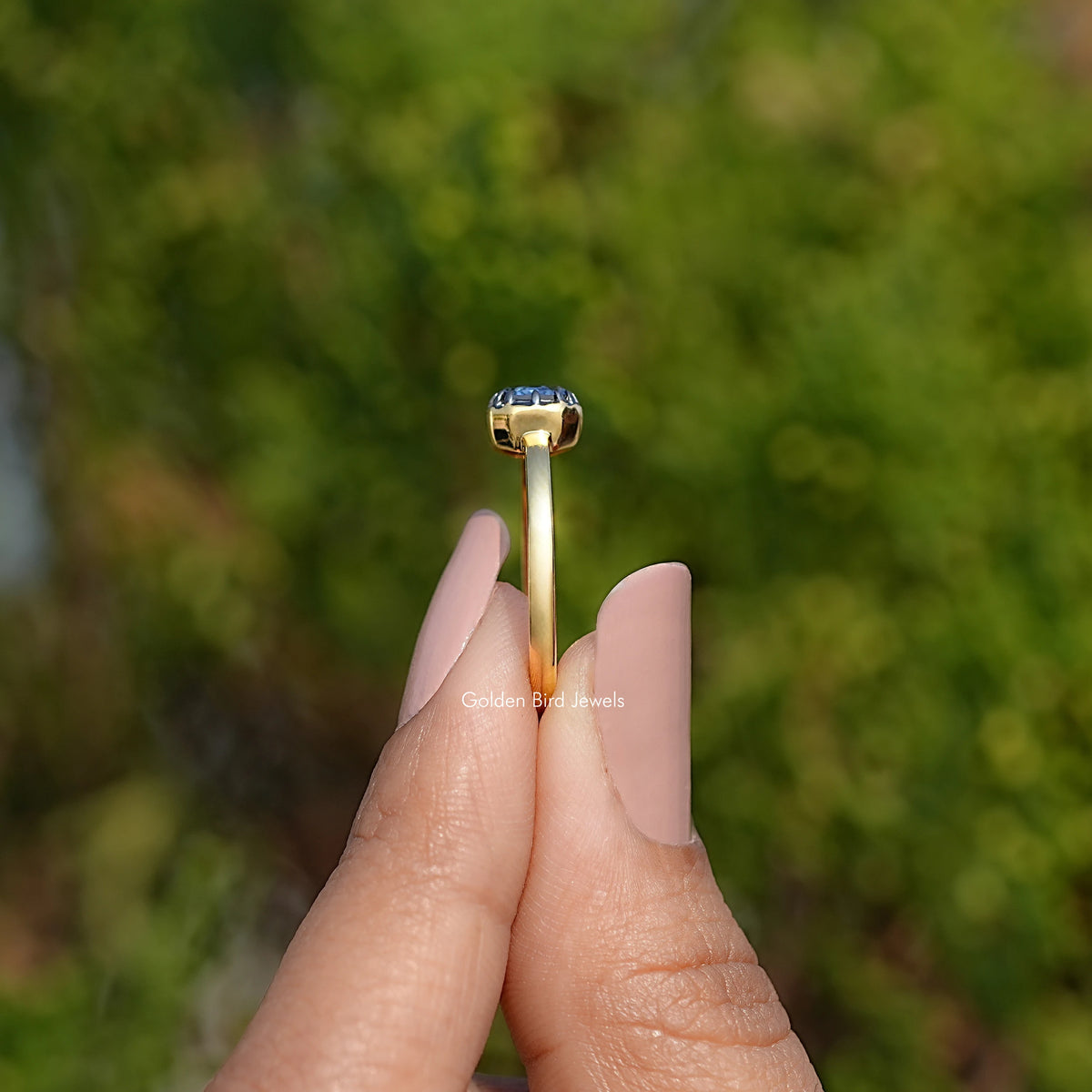 Gold solitaire ring with emerald-cut gemstone, underside view on finger