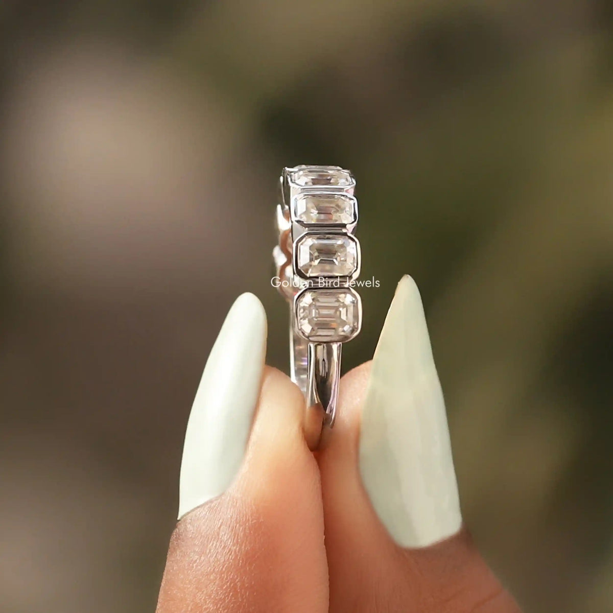 Silver half-eternity ring with emerald-cut clear stone bezels, side view